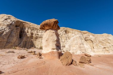 White and red sandstone toadstool hoodoo at Kanab Utah highlighted by blue sky and a white low mountain range. clipart