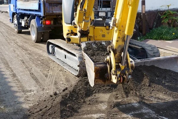 道路を修復し 掘削機は道路上の砂利をレベリングし アスファルトを敷設するための基盤を作っています — ストック写真