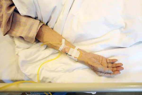 stock image Closeup of elderly patient hand with intravenous drip at the hospital bed 