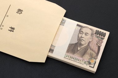 Siyah arkaplanda bir maaş çantasında Japonca on bin yen, çeviri: maaş, yıl, ay, gün. 