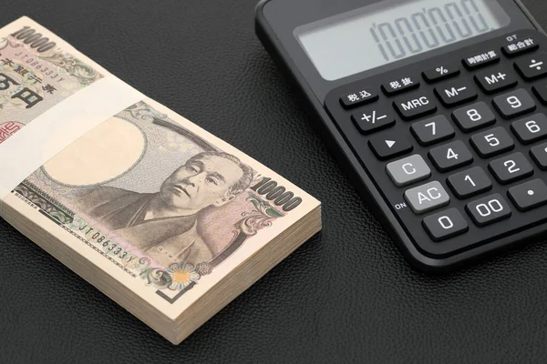 日本の給与封筒と電卓 紙幣は日本語で 000円 と書かれています ストックフォト