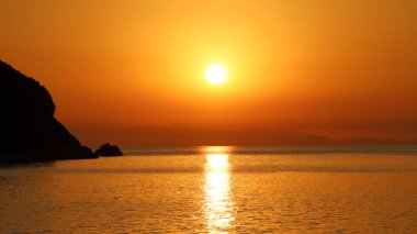 Sahilde gün batımında deniz manzarası. Deniz manzarasında parlayan parlak güneş ışığı  