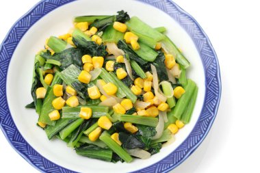 Mısır ve Japon Komatsuna sebze kızartmasını beyaz arka planda bir tabakta bırakırlar.