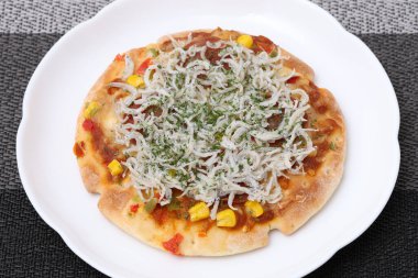 close up of small fish shirasu pizza on a plate on table   clipart