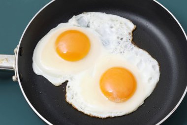 Arka plandaki tavada iki sahanda yumurtayı yakın.