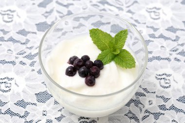 Yaban mersinli taze beyaz yoğurt, kahvaltı fincanı için nane yaprağı.