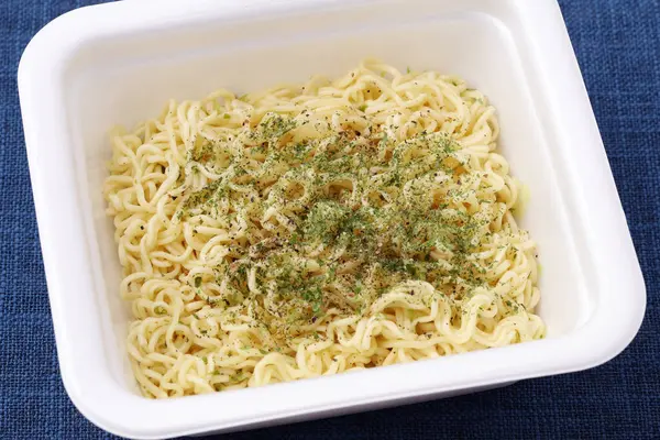 Instant salty sauce fried noodle in a white plastic cup on table 