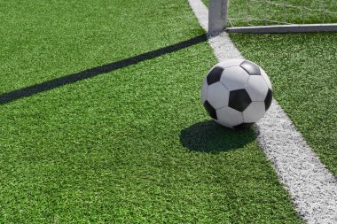 Futbol stadyumundaki kale çizgisinde yeşil çimlerin üzerinde bir futbol topu..