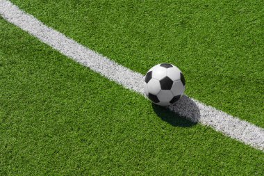 Futbol stadyumunda yeşil çimlerin üzerinde bir futbol topu..