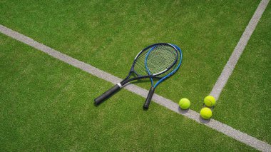 Kil kortunda sarı bir tenis topu ve tenis raketi yatıyor..