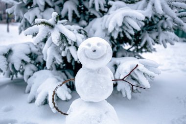 Smiling snowman. Makingsnowman in the forest from the first snow. Snowy winter, coniferous trees covered with snow