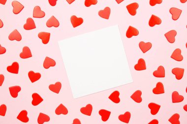 Mockup paper greeting card or wishes card on pink background. Pattern of red hearts, fountain pen for writing greeting and wishes, top view