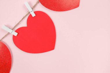 Garland of red hearts on clothespins on a pink background. Copy space, greeting card, space for text or message. Festive background