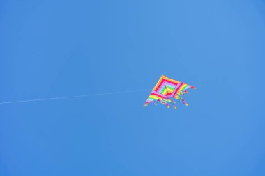 Colorful kite soars high in the sky Blue sky. Sports kite festival. Clean Monday in Greece. A flying kite with a wriggling tail. Copyspace, banner