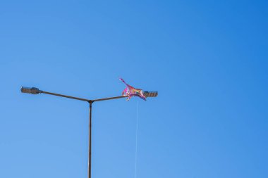 Colorful kite soars high in the sky Blue sky. Sports kite festival. Clean Monday in Greece. kite stuck on an electric pole. Copyspace, banner