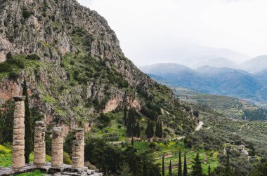 Antik bir tapınağın kalıntıları, Apollo Tapınağı Yunanistan Delphi Oracle 'da, görkemli dağ manzarasına karşı antik Yunan sütunları.