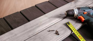 Tahta tahtalarda inşaat aletleri ve ekipmanları, çivili matkap veya tornavida ve ölçü cetveli, aletlerle ahşap atölye çalışması