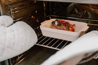 Çubuk tutacaklı eller fırından biftek alır. Kutlama Noel yemeği