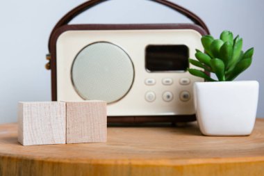 Gündüz planlama için hazırlanan ahşap bloklu verimli bir masa alanı, bir haber istasyonuna ayarlanmış klasik bir radyo ve etkin bir zaman yönetimi ve günlük esin kaynağı olan yaşam destekleyici sulu bir masa..