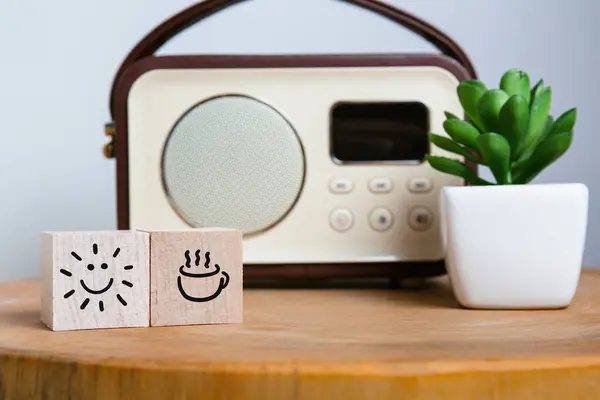 Envision your perfect morning with these mood-boosting icons on wooden blocks, a cup of coffee and a radiant sun, beside a nostalgic radio and a vibrant succulent plant.