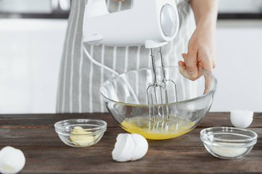 Önlüklü bir kadın ev yapımı fırın konseptiyle yumurta proteinlerini karıştırıyor.