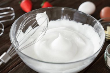 Kırbaçlanmış yumurta beyazı yumuşak ya da sert zirvelere çırpılmış cam karıştırma kabı, ahşap masa