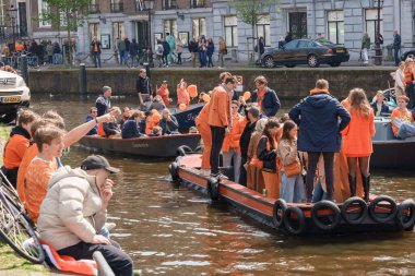 Turuncu giyen gülümseyen insanlar kanal tekne partisinin keyfini çıkarıyorlar Krallar Günü Hollanda, Amsterdam, 27.04.2023