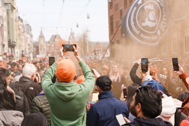 Krallar Günü 'nü kutlayan kalabalık turuncu kıyafetler giyer ve müzik performansı kaydeder. Hollanda, Amsterdam, 27.04.2023