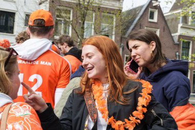 Turuncu elbiseli insanlar gülüyor ve konuşuyor, açık hava barında içki içiyorlar, Hollanda 'da Kral Günü' nü kutluyorlar - Hollanda, Amsterdam, 27.04.2023