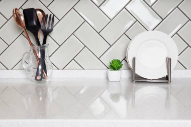 Temiz modern mutfak tezgahı, cam sürahide çatal bıçak, fayanslı arka plan, tabak tutacağı