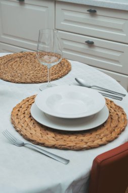 Şarap kadehi, beyaz tabaklar ve beyaz masa örtüsü örülmüş masa örtüsü..