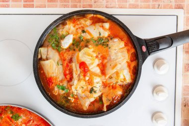 Ocakta domates sosunda haşlanan lahana ruloları, dolgulu lahana yaprakları, ev yapımı yemek tabağı.