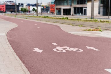 Modern binalarla çevrili şehir bölgesinde açık işaretli ve oklu modern bisiklet yolu.