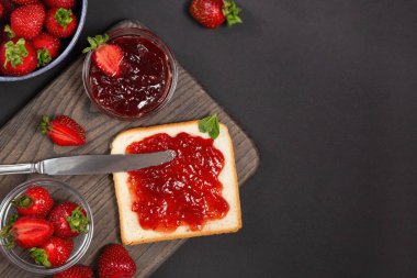 Çilek reçelli bir dilim ekmek kasede taze çilek ve arka planda bir bıçak..
