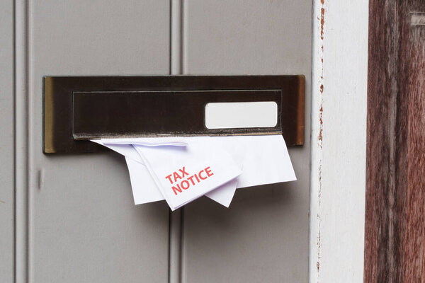 A tax notice letter is partially visible in a mail slot box, the arrival of important mail.