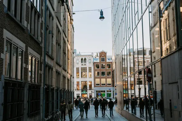 stock image People walk through a narrow street, contrast of old and new city - Netherlands, Amsterdam,12.11.2022