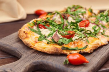 Ançüez, kırmızı soğan ve ahşap bir tahtanın üzerinde gebre otu olan bir İtalyan pizzası.