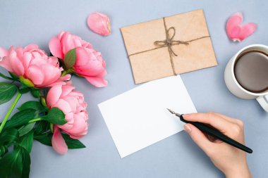 Kaligrafi kalemiyle el ele tutuşmak ve sabah boş karta kişisel mesaj yazmak, çiçek aranjmanı, zarf.