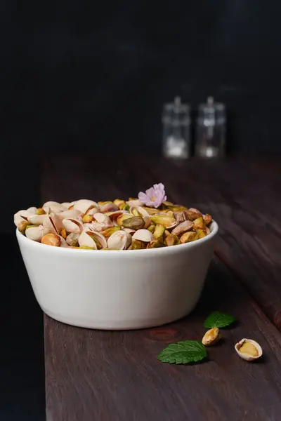 stock image Shelled and unshelled Pistachios filled white bowl placed on a dark wooden rustic table