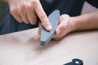 Eller keskinleştiren taşın üzerinde metal bir bıçak keskinleştirir, pişirme sırasında bıçağı kesme ve kesme için keskin hale getirir.