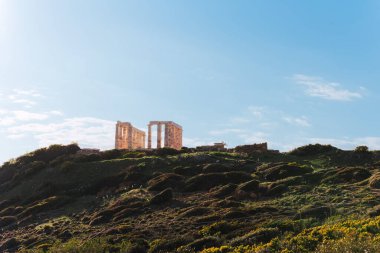 Cape Sounion 'daki Poseidon Tapınağı' nın uzak manzarası tepede, parlak mavi gökyüzünün altında, antik Yunan