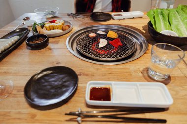 Sebzeli Kore barbekü masası. Yanında soslar, marul ve mezeler var.