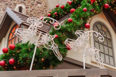 İki parıldayan ren geyiği Noel süslemesi kırmızı süslemeler ve şenlik ışıklarıyla çevrili bir çatıya monte edilir.