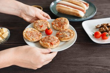 A plate with baked mini pizzas is shared at a table with other party bar snacks l for social dining clipart