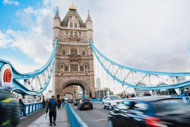 Araçlar ve insanlar Londra 'daki Tower Köprüsü' nde taş kulelerinin ve mavi süspansiyon kablolarının altından geçiyorlar - 04.01.2024, İngiltere, Londra
