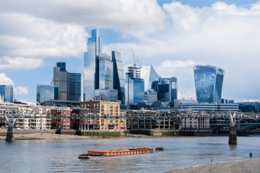 Londra finans bölgesinin yüksek binaları Millennium Köprüsü ve bir mavna ile Thames 'in arkasında yükseliyor - 04.01.2024, İngiltere, Londra