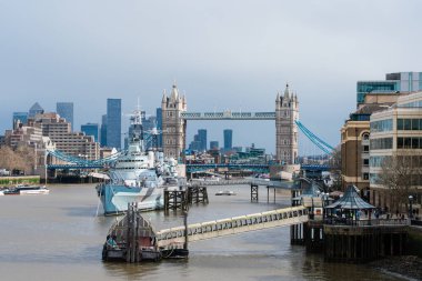 Londra 'daki Thames nehrine demirlemiş bir savaş gemisi, feribotlar 04.01.2024, İngiltere, Londra' dan geçerken Tower Bridge ile aynı hizada.