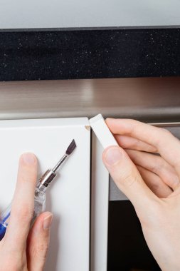 Beyaz dolaptaki hasarı onarmak için ısıtılmış spatula ve balmumu çubuğu kullanılıyor.