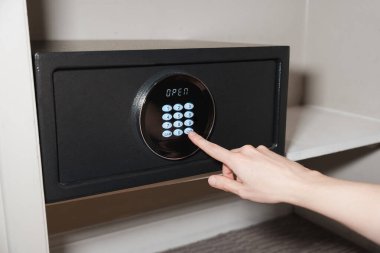 Bir kişi dijital bir otelin kasasına tuş takımını kullanarak şifreyi giriyor ve ekranda 