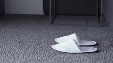 Uyandıktan sonra, çıplak ayaklı bir kadın beyaz terliklerini giyer ve güne halıda yumuşak terliklerle başlar.